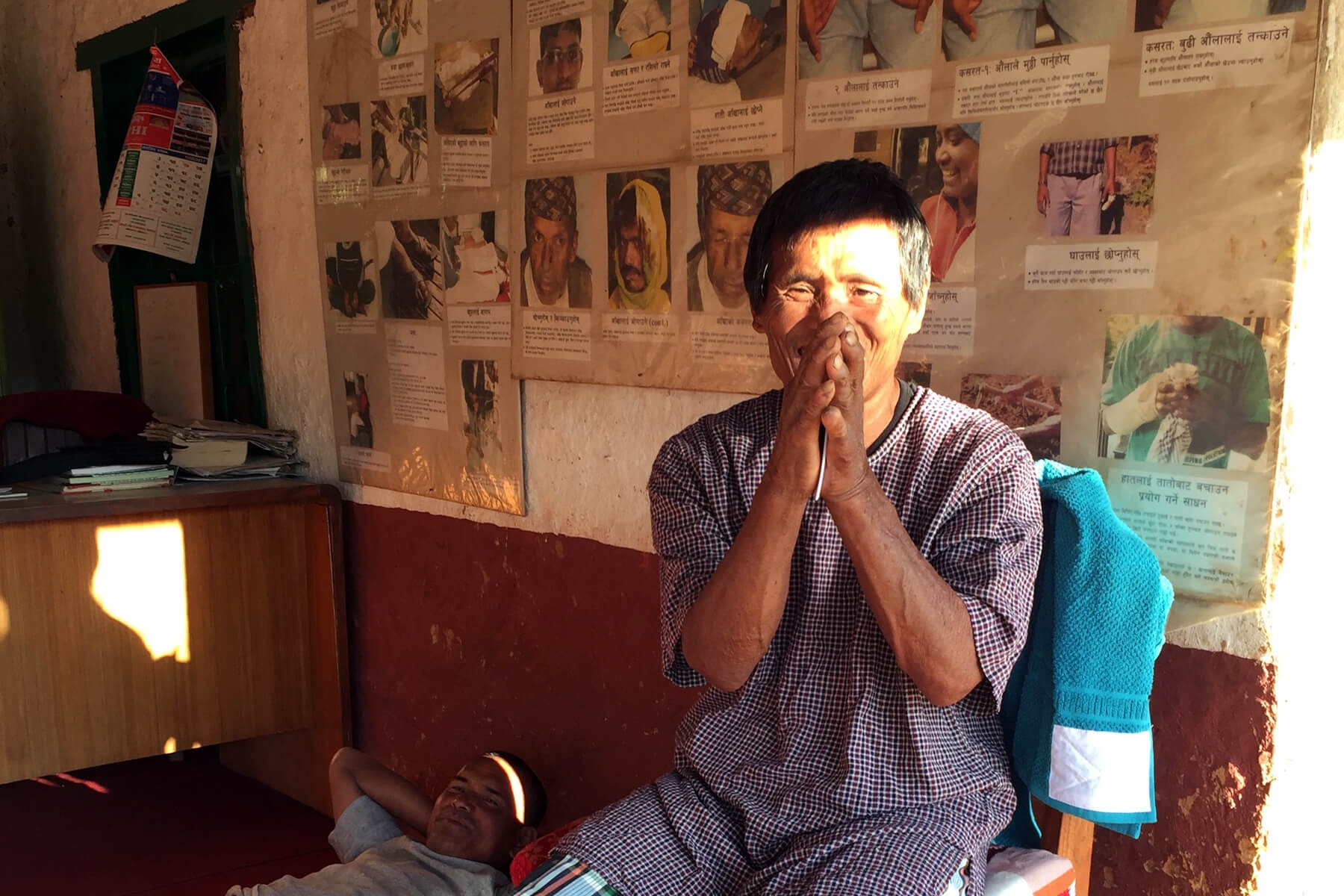 Ser Bahadur gestures the Nepali greeting of Namaste as he self-cares at Anandaban Hospital